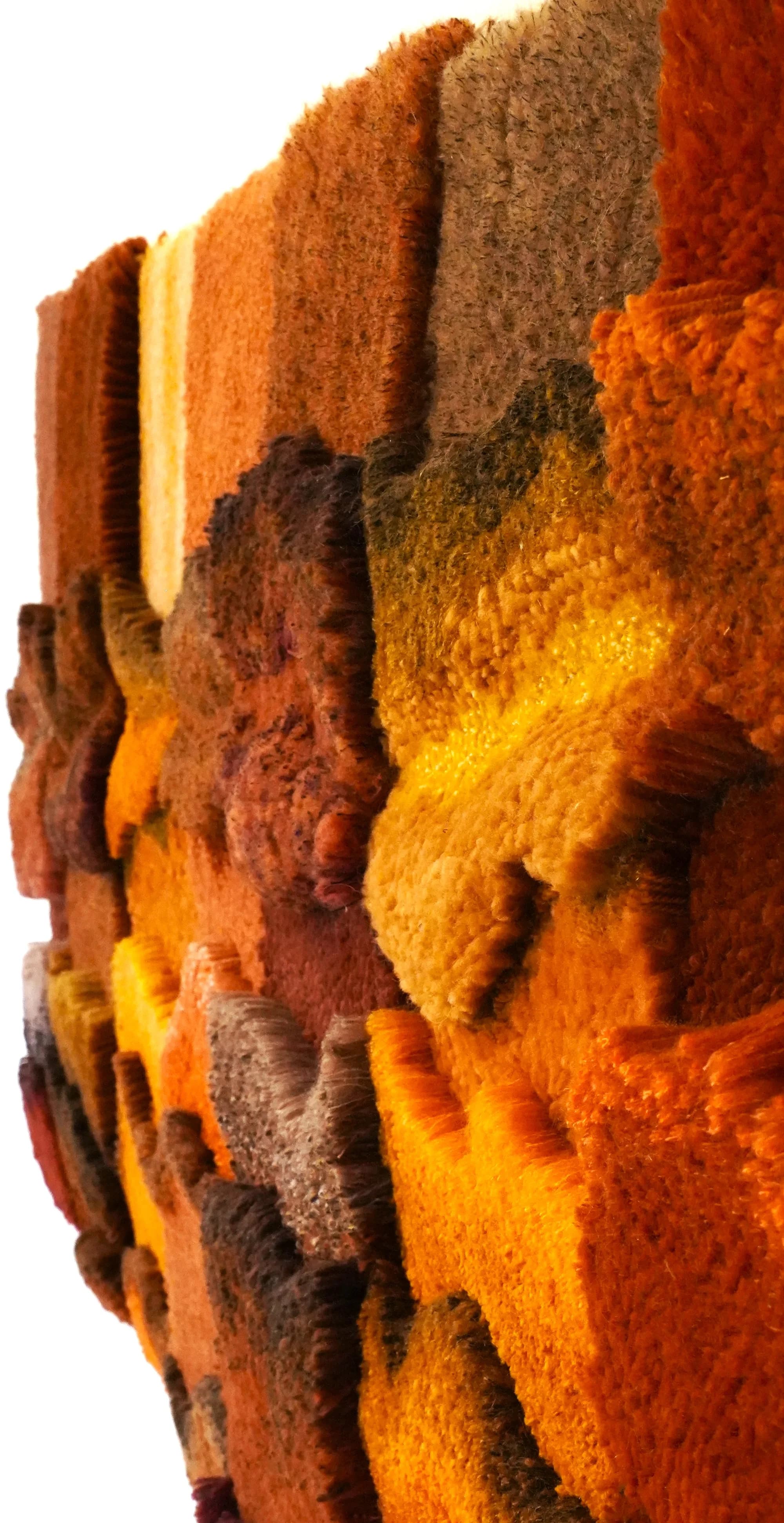 Close-up of a hand-tufted wool surface in warm amber and rust tones